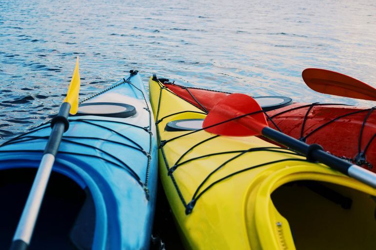 Kayaking on the Lake Concept Photo. Sport Kayak on the Rocky Lake Shore. Close Up Photo.
