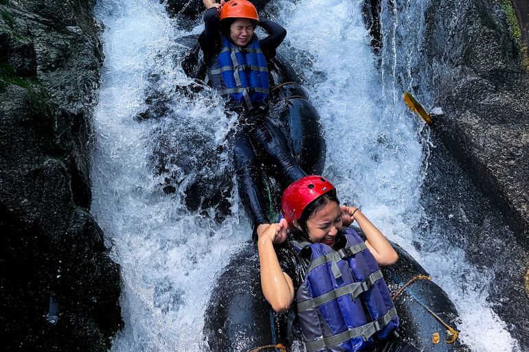 Kalipucung, Central Java, Indonesia – September 06 2024: Person sliding down a small waterfall using a river tube