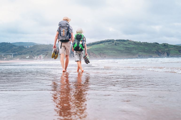 Father with son walk barefoot on the sand ocean beach