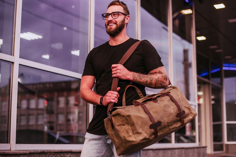 Man Casual Fashion. Man walking street with duffel canvas bag; Shutterstock ID 2156415749; purchase_order: aj; job: ; client: ; other: