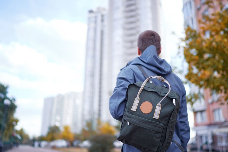 Back view of man with backpack on city street. المصدر: أدوبي ستوك