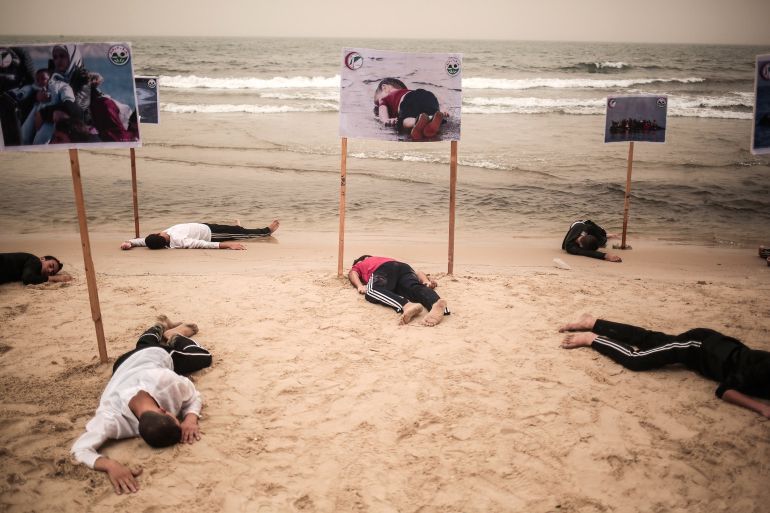 GAZA CITY, GAZA - SEPTEMBER 8: People lie on the Gaza beach to commemorate Aylan Kurdi, the three-year-old boy dressed in shorts and a red T-shirt, and 12 Syrians who drowned in the Aegean Sea after two boats filled with refugees en route to Greece sank, in Gaza City, Gaza on September 8, 2015. (Photo by Mustafa Hassona/Anadolu Agency/Getty Images)