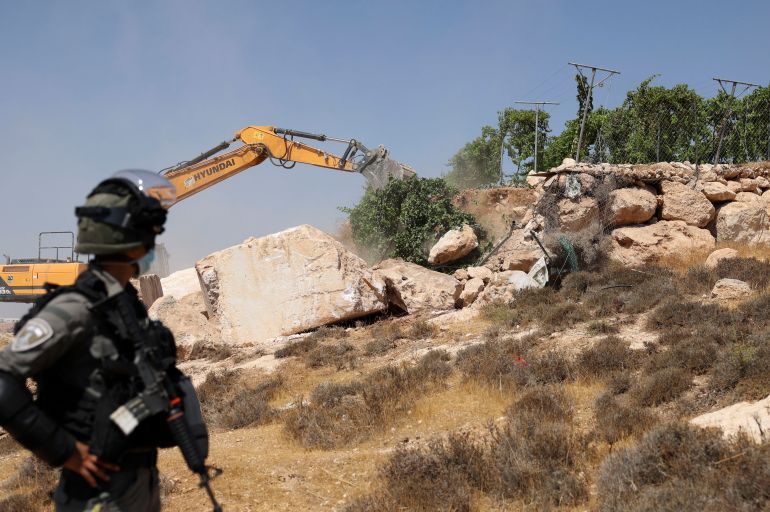 An Israeli bulldozer demolishes a Palestinian agricultural piece of land in area