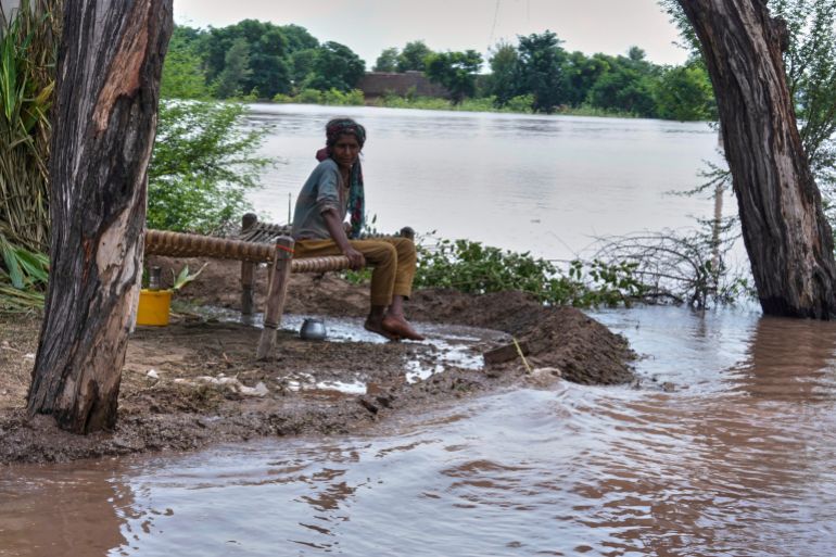A woman sits on a cot as floodwater approaches her village in Garh Maharaja, in Jhang district, Pakistan, Tuesday, Sept. 2, 2025. (AP Photo/K.M. Chaudary)