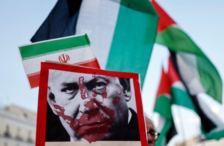 Protestors hold placards showing Israeli Prime minister Benjamin Netanyahu and Iranian and Palestinian national flags during a demonstration in support of Iran and condemnation of Israel's aggression in Madrid, on June 28, 2025.