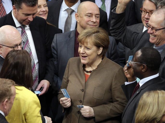 German Chancellor Angela Merkel, center right, holds her ballot card as she talks to lawmakers during a asylum debate of the German Federal Parliament, Bundestag, in Berlin, Germany, Thursday, Feb. 25, 2016. Germany's Parliament is debating new measures meant to speed up the handling of migrants and cut their numbers, as well as legislation making it easier to deport foreigners who commit crimes. Chancellor Angela Merkel's Cabinet has already approved the package of measures and they aren't expected to meet wide resistance in Thursday's vote. (AP Photo/Michael Sohn)