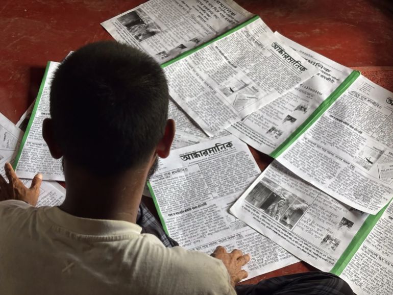 Hasan looks at copies of the May issue [Diwash Gahatraj/Al Jazeera]