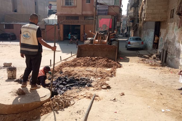 موظفو البلدية خلال أعمال صيانه للمناهل وتسلييك مجاري الصرف الصحي في أحد شوارع النصيرات (الجزيرة)