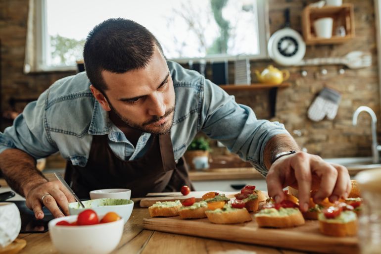 Young chef making bruschetta while preparing food in the kitchen.